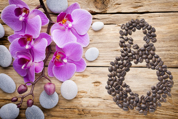 Fototapeta na wymiar Coffee beans in form of number eight and orchids on beautifull background. International women's day. 8th march
