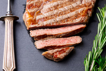 Grilled sliced beef steak on slate stone table. Top view.