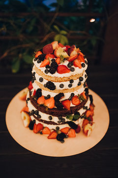 wedding cake decorated with cream and berries, stands on a table in the banquet area