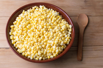 Frozen corn in a bowl with a wooden spoon