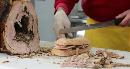  chef-kok die het vlees van varkensvlees snijdt om een broodje in het eten te bereiden © ChiccoDodiFC