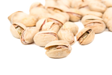 Salted pistachios are scattered on a white background