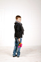 Boy full-length with red tulips in hands smiling shyly