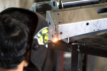 Worker welding the sheet metal part by manual