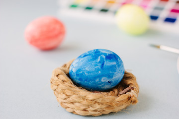Deep blue easter egg on nest over bright background.