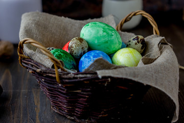 Colored easter eggs on basket over rustic table.