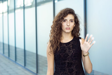 Frightened curly girl holds open hand, biometric verification. Preservation and identity theft.