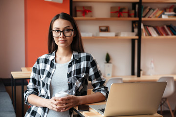 Pretty young caucasian lady using laptop and drinking coffee.