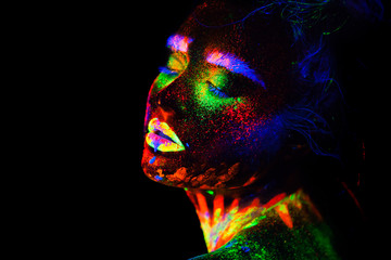 Beautiful extraterrestrial model woman in neon light. It is portrait of beautiful model with fluorescent make-up, Art design of female posing in UV with colorful make up. Isolated on black background