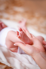Tenderness of motherhood in one touch. The mother holds the foot of a newborn baby