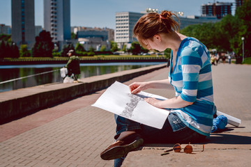 young girl draws a sketch of city 