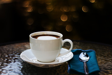 Hot cup of coffee in white on a dark background.