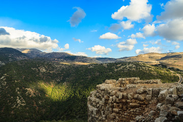 Upper Galilee mountains landscape stones, rocks and ruins of ancient fortress, Golan Heights background, beautiful blue sky, road, north Israel view. Concept: travel, history and nature