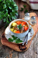 Fish soup with potatoes, carrots and parsley on the old wooden background.