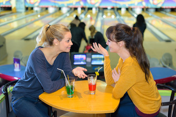 Woman sat at table chatting in bowling hall - obrazy, fototapety, plakaty
