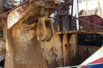 Closeup of  trawler cable warp pulley on the stern of a steel fishing boat with rust and corrosion by salt water