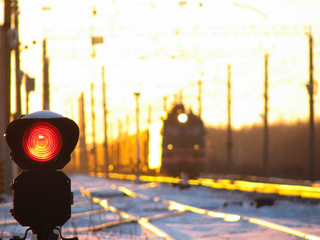 Railway traffic light shows blue signal on railway with blur effect and railway with freight train...