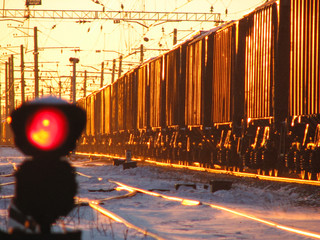 Railway traffic light shows blue signal on railway with blur effect and railway with freight train...