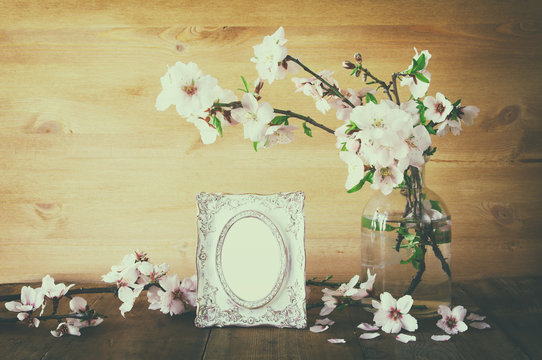 Vintage blank photo frame next to spring flowers