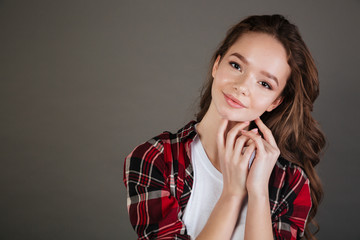 Happy lovely young woman in plaid shirt standing and smiling