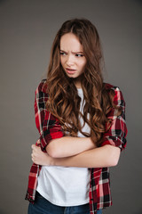 Angry irritated woman in plaid shirt standing with arms crossed