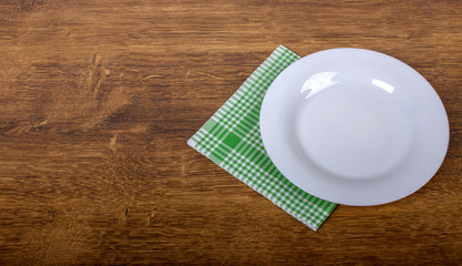 Empty plate and towel on the wooden table background