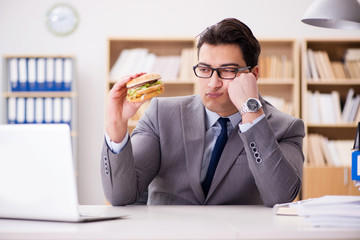 Hungry funny businessman eating junk food sandwich