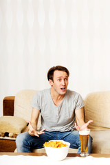 Happy young man watching sports on TV