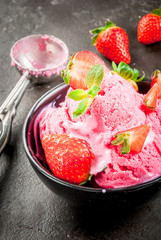 Strawberry ice cream pink with strawberries and mint. In a small bowl, on the black concrete table