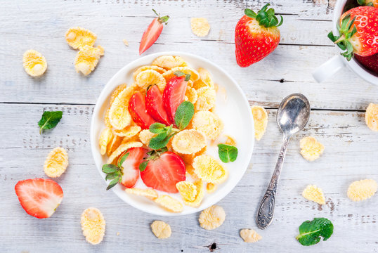Summer light breakfast: homemade organic yogurt with cornflakes and fresh strawberries. On a white rustic wooden table copy space top view