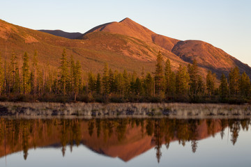 Mountain in red light and the reflection in the lake. Lake Labynkyr. Yakutia. Russia.