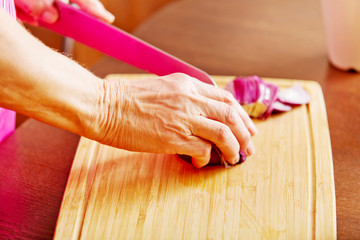 Obraz na płótnie Canvas Woman cut red onion on cutting board
