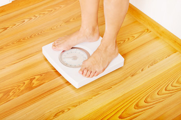 Senior woman standing on weight scale in living room