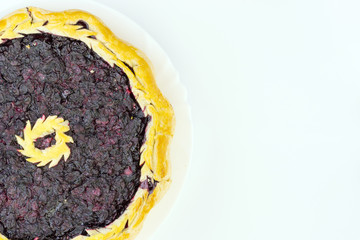 Homemade honeyberry pie in white plate on white background, top view