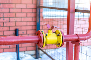 distributor gas pipes in a residential complex, the gas valve on a background of red brick wall