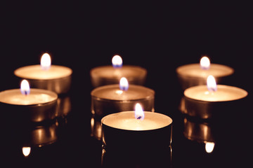 Group of tea candles on a black background. Selective focus