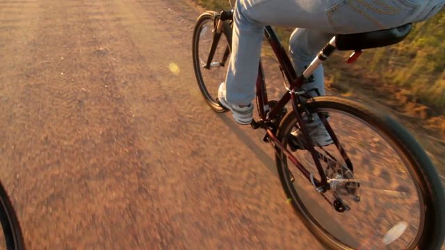 Girl riding bike during golden hour time. Young woman bicycling on gravel road during afternoon
