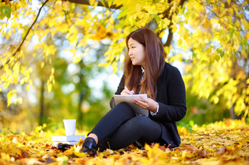 Young asian woman studying/working and enjoying sunny autumn day