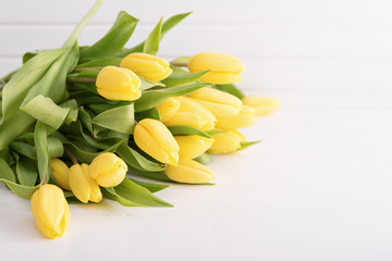 Fresh yellow tulips on white wooden table