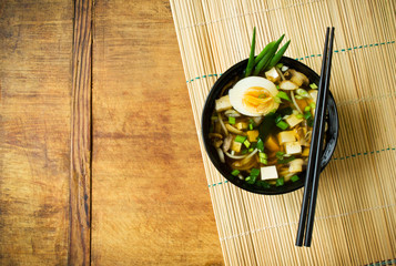 Asian soup in bowl on bamboo mat with copy space