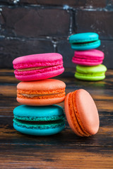 Colourful macaroons or macarons, pink, blue, green and orange ones on the dark wooden rustic table.