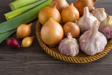 Onions, leeks and garlic on the table in the kitchen. Healthy eating and lifestyle.