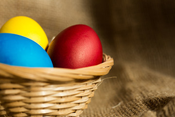 Colored Easter eggs in a basket on a rustic background