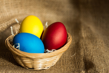 Colored Easter eggs in a basket on a rustic background