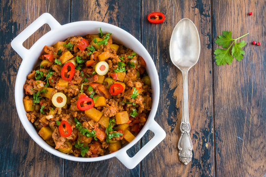 Picadillo, A Stew Of Ground Beef And Tomatoes, With Raisins And Olives In A White Casserole. Wooden Table, Top View.