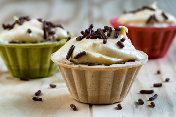 Vanilla cream cupcake with chocolate granules on a wooden table