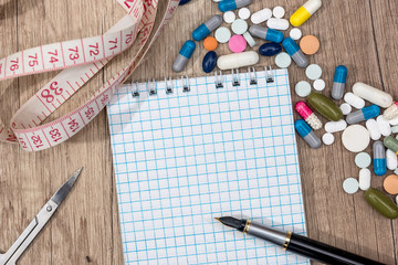 fitness concept of weight loss - notepad, pills, meter, calculator.