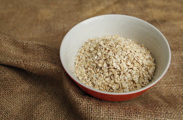 Bowl of dry oatmeal on rustic textile