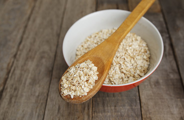 Dry oatmeal in wooden spoon, rustic background