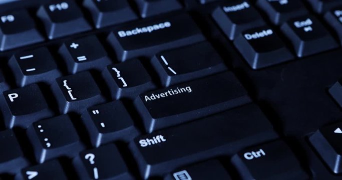 Close up of a male hand pressing an Advertising button on the computer keyboard
